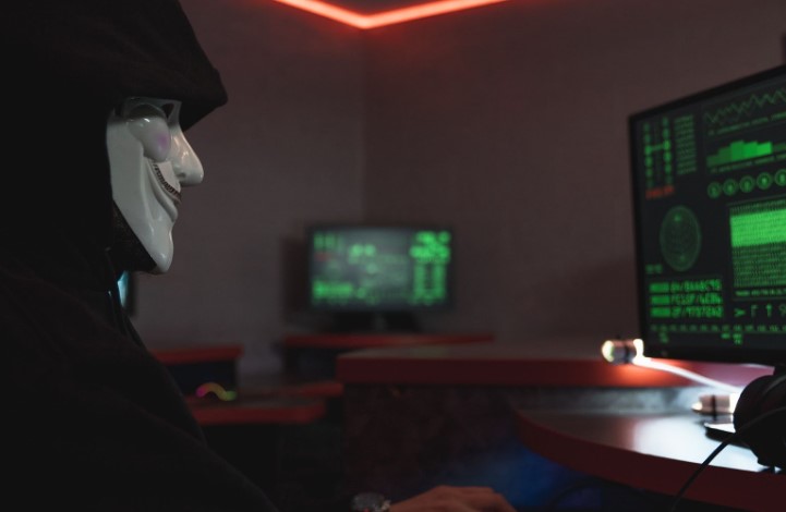 A person in a mask in front of the computer