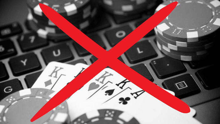 A laptop with cards and casino chips on the keyboard, all crossed out